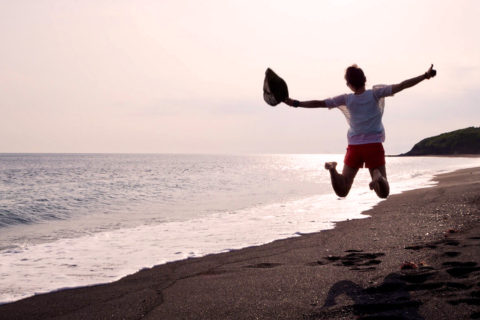 やさしいオレンジ色に染まった海と黒い砂浜〈伊豆大島 砂の浜〉